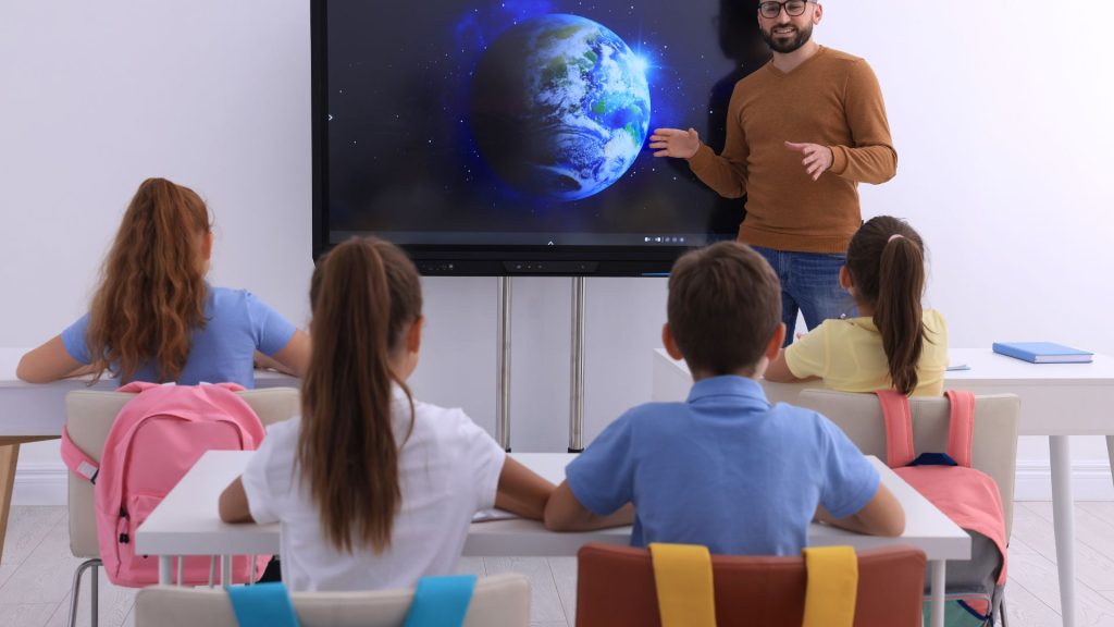 Teacher using an interactive display for meetings to present a multimedia lesson.